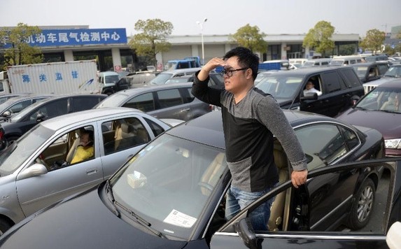 Cars queue up to get licensed in Hangzhou, capital of east China's Zhejiang Province, March 25, 2014. Hangzhou will carry out vehicles number control and peak restriction on Wednesday to tackle traffic jams and urban pollution. (Xinhua/Han Chuanhao)   