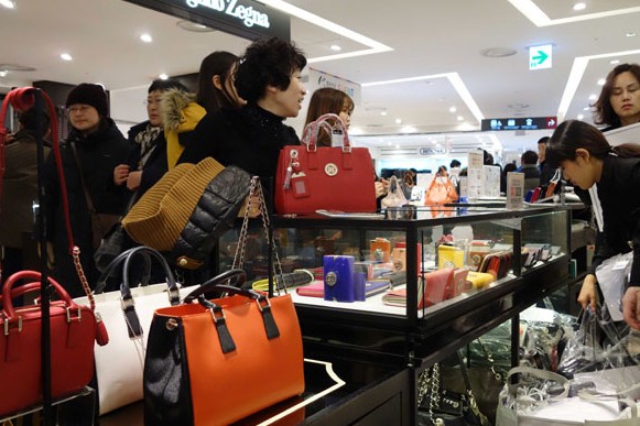 Chinese tourists buy luxuries at a duty-free shop in Seoul. China will overtake the US this year as the largest overseas tourism market measured by travelers and, continue to grow, experts say. The number of Chinese families able to afford overseas holidays is expected to double in the next 10 years. LIU DEBIN/CHINA DAILY  