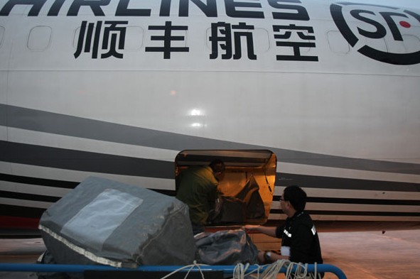 A worker unloads packages from a Shenzhen-based SF Express (Group) Co cargo aircraft in Nantong, Jiangsu province. [Photo/CHINA DAILY]  