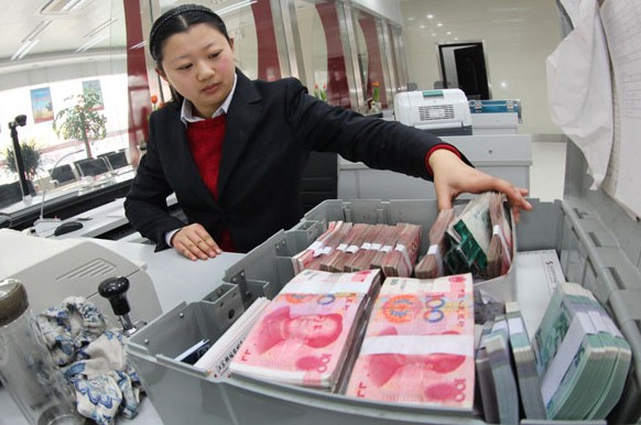 An employee prepares money at a commercial bank in Ganyu, Jiangsu province. New loans stood at 1.05 trillion yuan($169 billion)in March, up from an average of 981.8 billion yuan in January and February. SI WEI/CHINA DAILY  