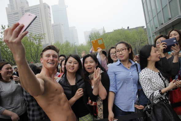 A model of Abercrombie & Fitch takes selfies with visitors during a media preview of its new flagship store in Shanghai on Thursday. The four-story shop, its first flagship store on Chinese mainland, will open on Saturday. Yang Lei / For China Daily