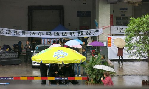 Laid-off Wal-Mart workers guard the closed store as people hired by Wal-Mart (front, in black) try to remove goods still in the store in Changde on March 22. Photo: Li Qian/GT
