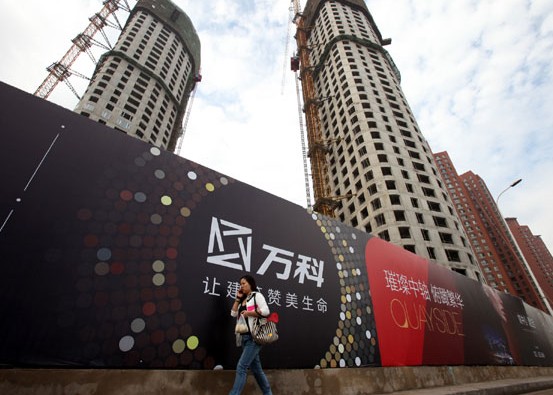 A pedestrian walks past a construction site of a residential apartment project developed by China Vanke Co Ltd in Tianjin. The company posted 1.53 billion yuan in net profits in the first quarter, registering the first year on year drop of 5.23 percent in 13 years. Provided to China Daily  