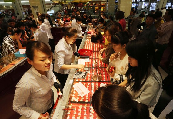Customers choose gold jewelry at a shop in Xuchang, Henan province, during the May Day holiday. China's gold jewelry consumption jumped 30.2 percent year-on-year in the first quarter of this year to 232.53 metric tons. GENG GUOQING/CHINA DAILY  