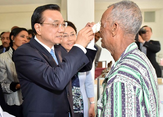 Premier Li Keqiang removes gauze from an Ethiopian cataracts patient who regained his eyesight after surgery performed by Chinese doctors at a hospital in Addis Ababa, the Ethiopian capital. A team of Chinese ophthalmologists has been providing its services for free at the hospital, which Li visited on Tuesday. [Photo / Xinhua]