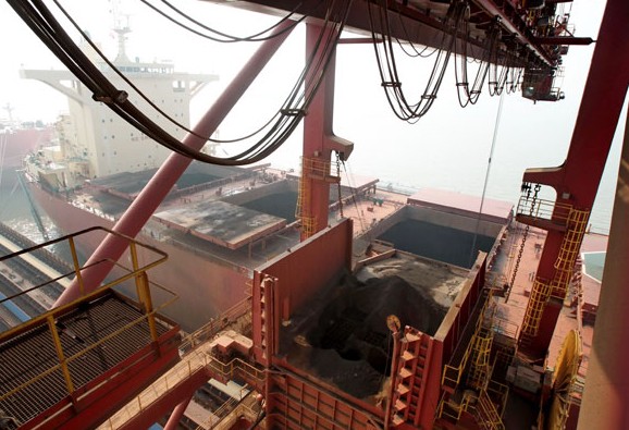 Imported iron ore is unloaded from a vessel in Nantong, Jiangsu province. Xu Congjun / For China Daily  