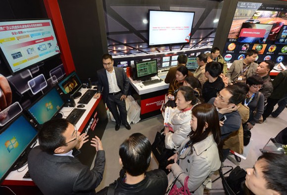 Visitors at Lenovo Group's booth look at the company's products at a trade show in Beijing in March. Provided to China Daily  
