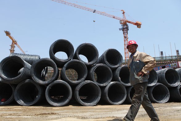 A worker walks past steel products in Rizhao, Shandong province. China's preliminary Purchasing Managers Index was 49.7 in May, according to HSBC Holdings Plc and Markit Economics. Provided to China Daily  