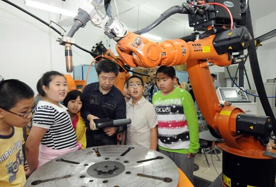 A technician in Harbin, capital of Heilongjiang province, explains to children how a robot works. About 36,560 industrial robots were sold in China last year, up 60 percent from 2012. Liu Yang / For China Daily