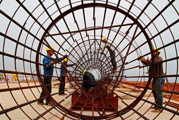 Workers assemble steel frames for a pier at a railway bridge construction site in Pingtan, Fujian province. China has become too dependent on credit and investment since the global financial crisis in 2008, the IMF said. [Photo/China Daily]  