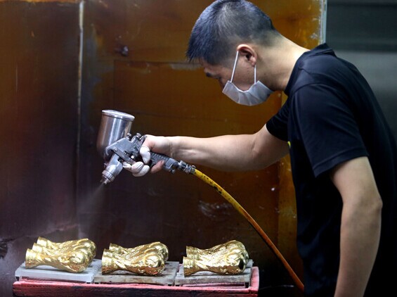 A worker at Dongguan Wagon Enterprise in Guangdong province makes Word Cup trophies on Wednesday. Chen Fan/For China Daily