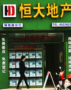 A customer walks past an Evergrande sales outlet in Yichang, Hubei province. Some leading domestic developers remain optimistic that inelastic demand from first-time buyers will revive transactions in second- and third-tier cities. Zhou Jianping / For China Daily
