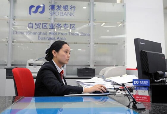 An employee handles a transaction at an SPD Bank Co Ltd branch in Shanghai. Banks in Shanghai can offer deposit rates on their own for corporate foreign-currency accounts with balances below $3 million. Provided to China Daily