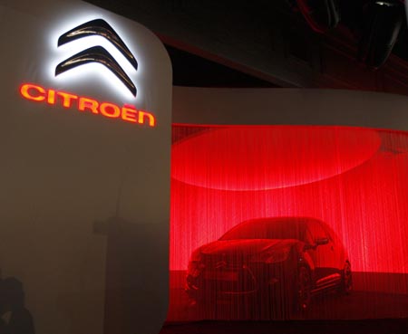 A new concept car is about to be unveiled next to the new Logo of French car maker Peugeot-Citroen during a news conference in Paris, February 5, 2009. [File Photo: Xinhua]