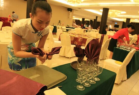 A waitress fans a cloth napkin at a hotel restaurant in Foshan, Guangdong province. CHINA DAILY