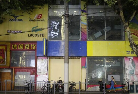 A pedestrian passes by a row of shuttered shops along Huaihai Road in Shanghai. Gao Erqiang / China Daily  