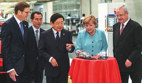 Visiting the terminal of assembly production line, Martin Winterkorn (first from right), chairman of the board of management of Volkswagen AG, and Xu Jianyi, chairman of FAW (third from left), present a gift to the German Chancellor Angela Merkel. Provided to China Daily  