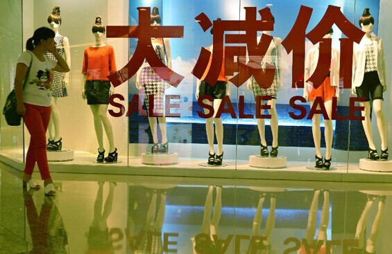 A customer walks past a shop window at a department store in Hangzhou, capital of east China's Zhejiang Province, July 15, 2014. China's economy grew 7.4 percent year on year in the first half of 2014, the National Bureau of Statistics (NBS) announced on July 16. (Xinhua/Long Wei)