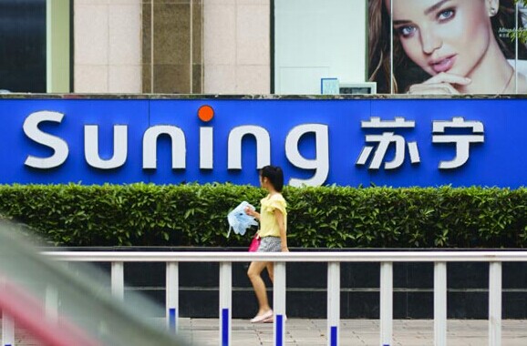 A resident of Yichang, Hubei province passes by a logo of Suning Commerce Co Ltd. Suning's online operations saw first-half revenue increase 51 percent to 8.3 billion yuan. Zhou Jianping / For China Daily  