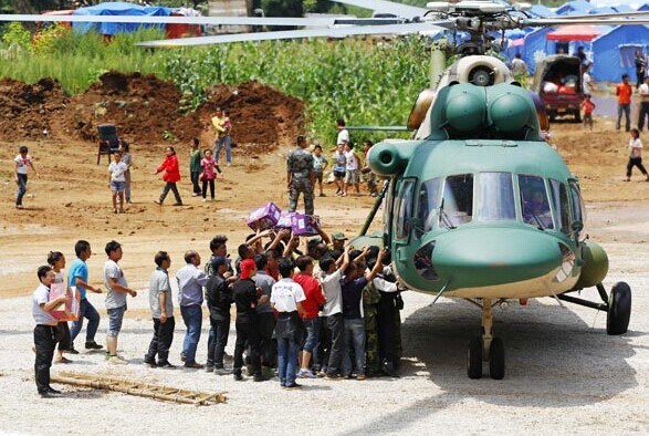 Earthquake relief supplies are offloaded from a helicopter in Longtoushan town of Ludian county, Yunnan province. [Photo/Xinhua]