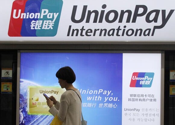 A woman walks past a UnionPay International advertisement in Seoul, South Korea. The Chinese bank card service company plans to expand its business in Russia. [Photo/Xinhua]