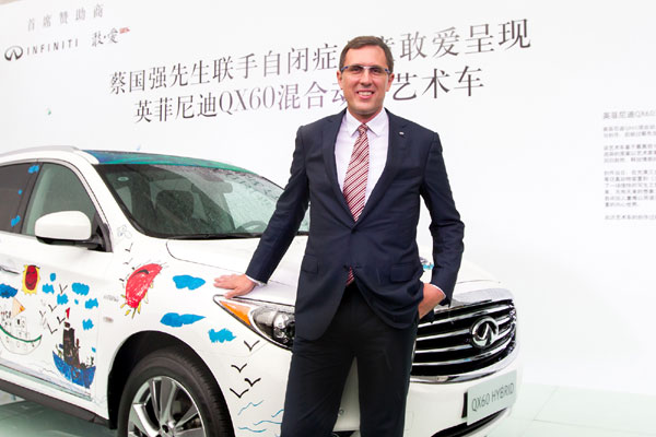 Daniel Kirchert, managing director of Infiniti China, with the QX60 Hybrid painted by 15 children, including eight with autism. [Provided to China Daily]