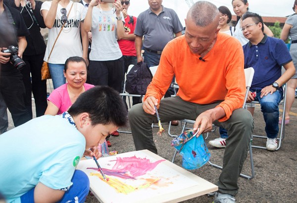 Artist Cai Guoqiang gives painting lessons to a boy with autism. [Provided to China Daily]
