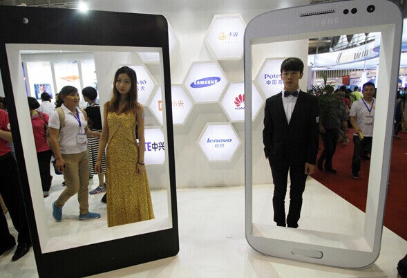 Models promote smartphones at a fair in Nanjing, Jiangsu province. Major telecom carriers are cutting operating expenses and downsizing subsidies to contracted smartphones. [Provided to China Daily]  