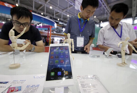People look at the new handset during a mobile phone trade fair on June 27, 2014. [Provided to China Daily]