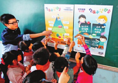 A Mondelez China employee volunteer teaches students nutrition knowledge at Haihong Primary School in Shanghai where Mondelez set up a kitchen. [Provided to China Daily]  