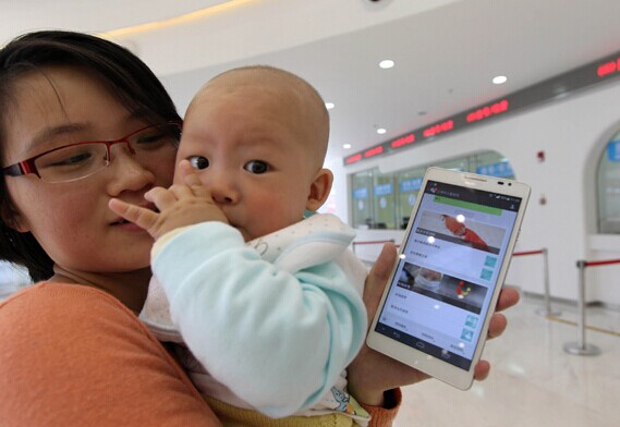 A parent shows an online registration service powered by Wechat platform in a hospital in Shanghai, April 10, 2014. [Photo/Xinhua]