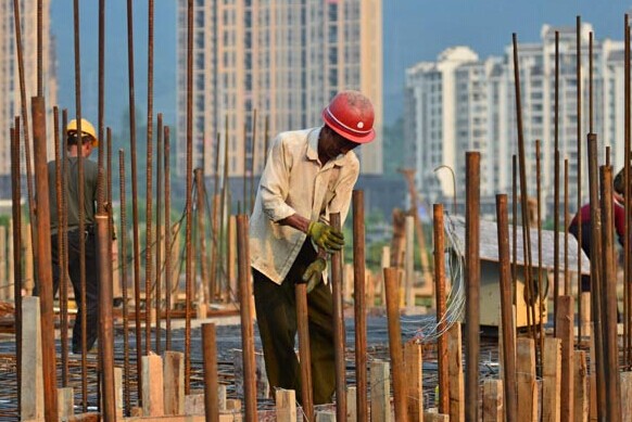Workers at a property project in Chenzhou, Hunan province. Property developers are facing the pressure of a decline in net profits in the first half of 2014. [Photo/China Daily]  