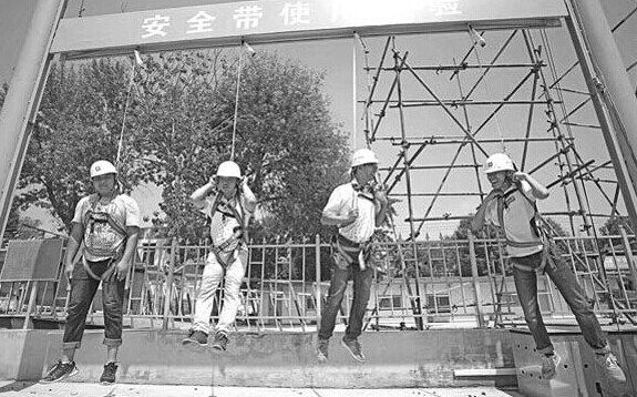 Four construction workers practice using a safety belt at a training and experience-building site in Tianjin this month. The site, the first of its kind in Tianjin, covers 300 square meters and consists of 11 modules, including those for the safe use of electricity and helmets. Liu Dongyue / Xinhua