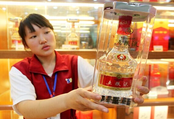 A sales assistant showcases a bottle of Wuliangye white spirits at a supermarket in Ganyu county, Jiangsu province. Wuliangye Group Co Ltd reported record low profits and sales in the first six months of this year. [Photo/China Daily]  