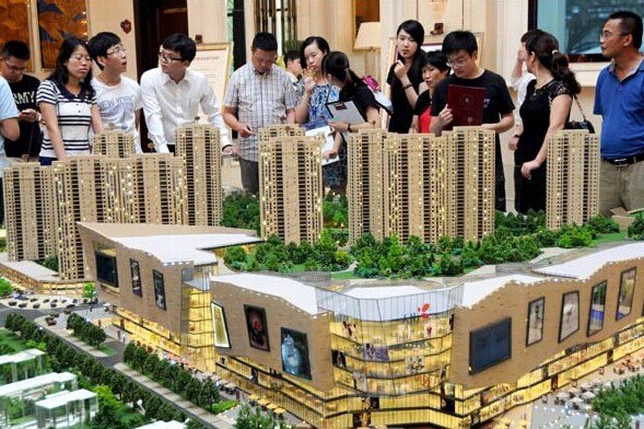 Potential homebuyers examine a property project model in Hangzhou, capital of Zhejiang province, on Sunday, after the city lifted all restrictions on property purchases. XINHUA  