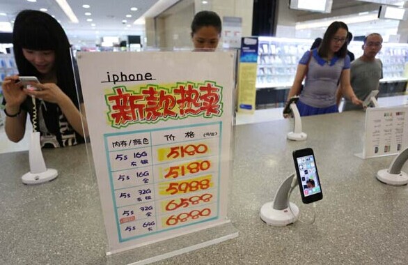 Customers look at iPhone devices at a store in Xuchang, Henan province. China Mobile began to take preorders for the iPhone 6, to be released by Apple Inc on Sept 9 in San Francisco. XU ZHONGYUAN/CHINA DAILY  