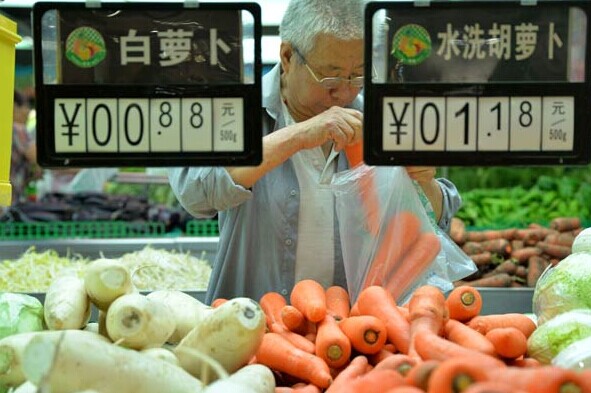 A customer buys carrots at a supermarket in Handan, Hebei province, on Thursday. Food prices rose 3 percent and were the main driver of inflation in August, according to the National Bureau of Statistics. HAO QUNYING/CHINA DAILY  