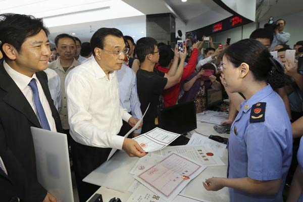 Premier Li Keqiang visits the Comprehensive Service Center of the China (Shanghai) Pilot Free Trade Zone on Thursday morning. DING LIN/CHINA DAILY
