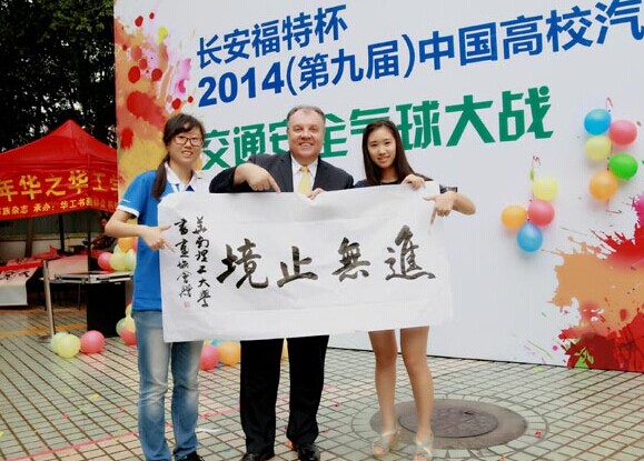 Marin Burela (center), president and CEO of Changan Ford Automobile Co, receives calligraphy that says 'going further' from student representatives at South China University of Technology, a host of their debate series. [Photo/China Daily]