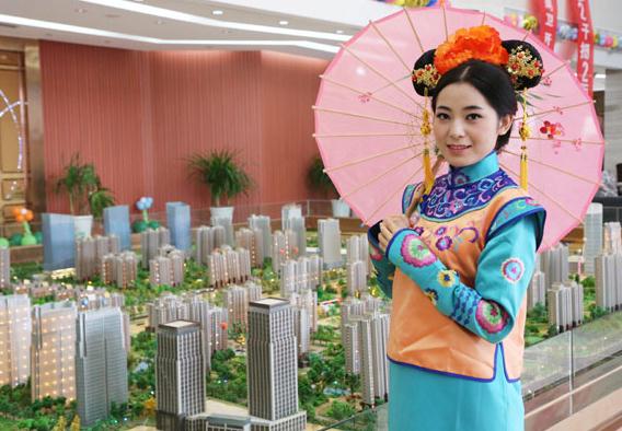 A saleswoman dressed in Qing Dynasty (1644-1911) Manchurian costume promotes a real estate project in Xuchang, Central China's Henan province. Developers across the country have used creative marketing schemes to grapple with continuous downturn. [Geng Guoqing / China Daily] 