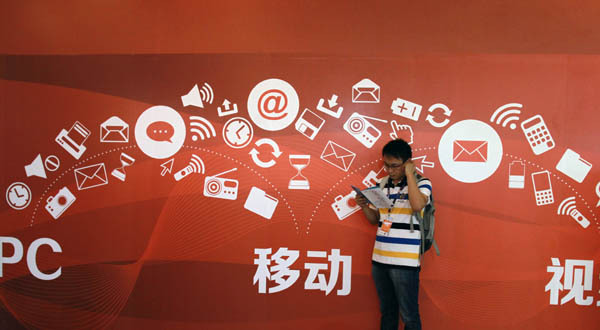 A visitor reads a brochure in front of a promotional board at the opening of the 2014 China Internet Conference on Aug 26 at the Beijing International Convention Center. [Provided to China Daily]  