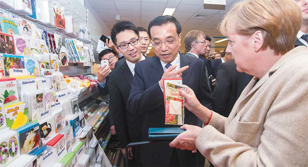 Premier Li Keqiang and German Chancellor Angela Merkel examine greeting cards in a Berlin supermarket on Friday. (Wang Ye / Xinhua)