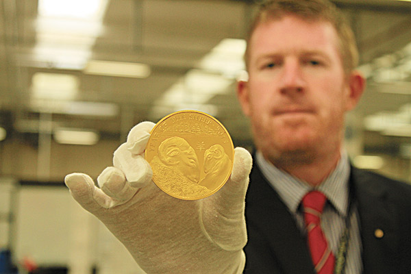 An employee at the Royal Mint shows the lunar coin with the Chinese zodiac's sheep sign. [Provided to China Daily]  