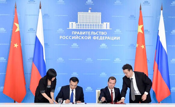 Premier Li Keqiang (L) and Russian Prime Minister Dmitry Medvedev sign a joint statement following the 19th China-Russia Prime Ministers' Regular Meeting in Moscow on Oct 13, 2014. [Photo/Xinhua]  