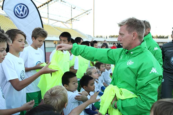 Roy Präger, the former star football player and the current head of Youth Football School with VfL Wolfsburg, hands over jerseys to young players before the training session in Beijing, Oct 15, 2014. [Photo provided to chinadaily.com.cn]
