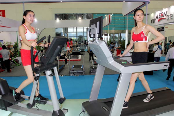Models help promote treadmills at a sports equipment fair in Wuhan, Hubei province. Sports industry is expected to account for about 1 percent of the GDP by 2025, from 0.6 percent in 2012. SUN XINMING / CHINA DAILY  