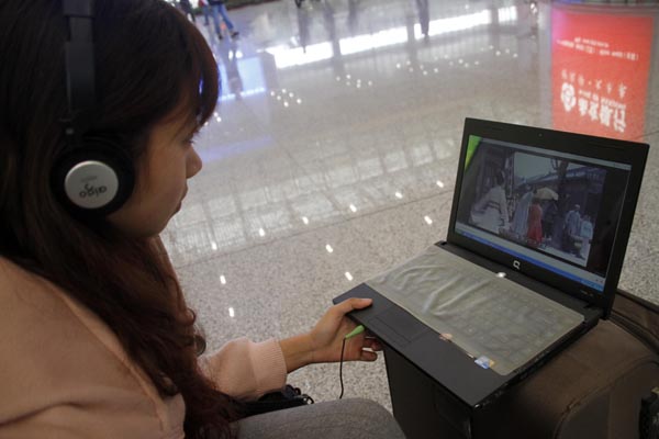 A passenger watches a movie on her notebook computer in the waiting room of a railway station in Nanjing, capital of Jiangsu province. Most of the movie promotions are expected to go mobile sooner or later. [Provided to China Daily]  