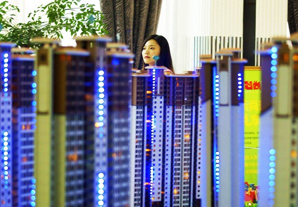 A customer checks out models of housing projects at a real estate firm in Yichang, Hubei province. Residential property sales in the first nine months of the year slumped 10.8 percent year-on-year, the largest fall since April 2012. [Provided to China Daily]  