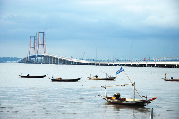 Fishing boats near the Suramadu Bridge, the longest of its kind in Indonesia. The bridge was built by a consortium including China Harbor Engineering, one of many constructed by Chinese companies in the country in recent years. [Provided to China Daily]  