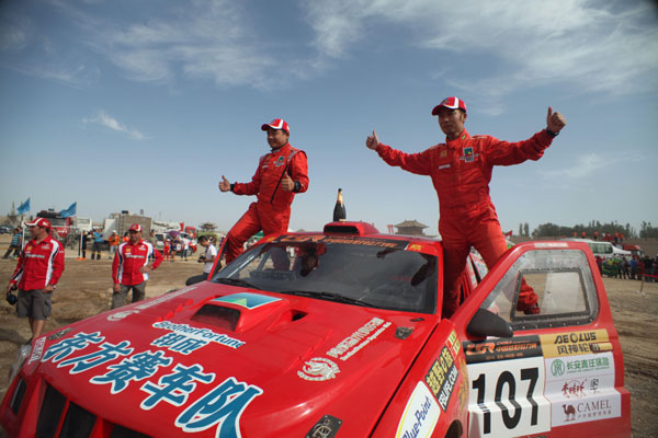 Racing car drivers Ma Miao (right) and Liao Min of East Racing Team celebrate after winning the third achievement at the second China Grand Rally in Dunhuang, Gansu province. [Provided to China Daily]  